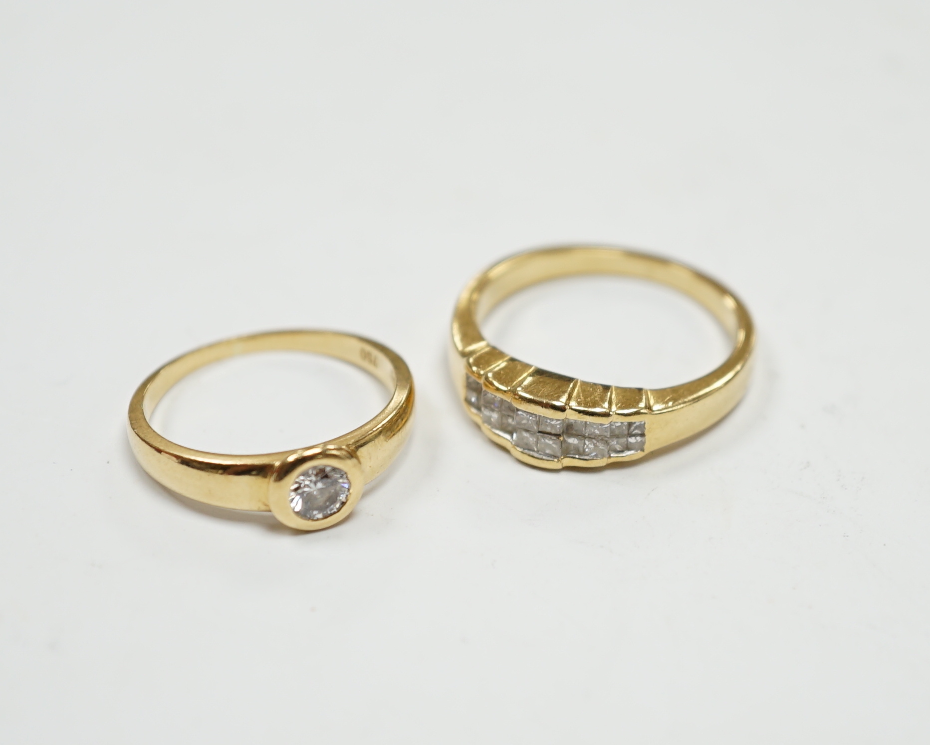 A 750 yellow metal and collet set solitaire diamond ring, size L and a yellow metal and diamond cluster set half hoop ring, size O, gross weight 7.4 grams